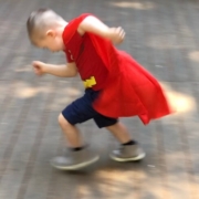 child running in an action pose wearing a cape